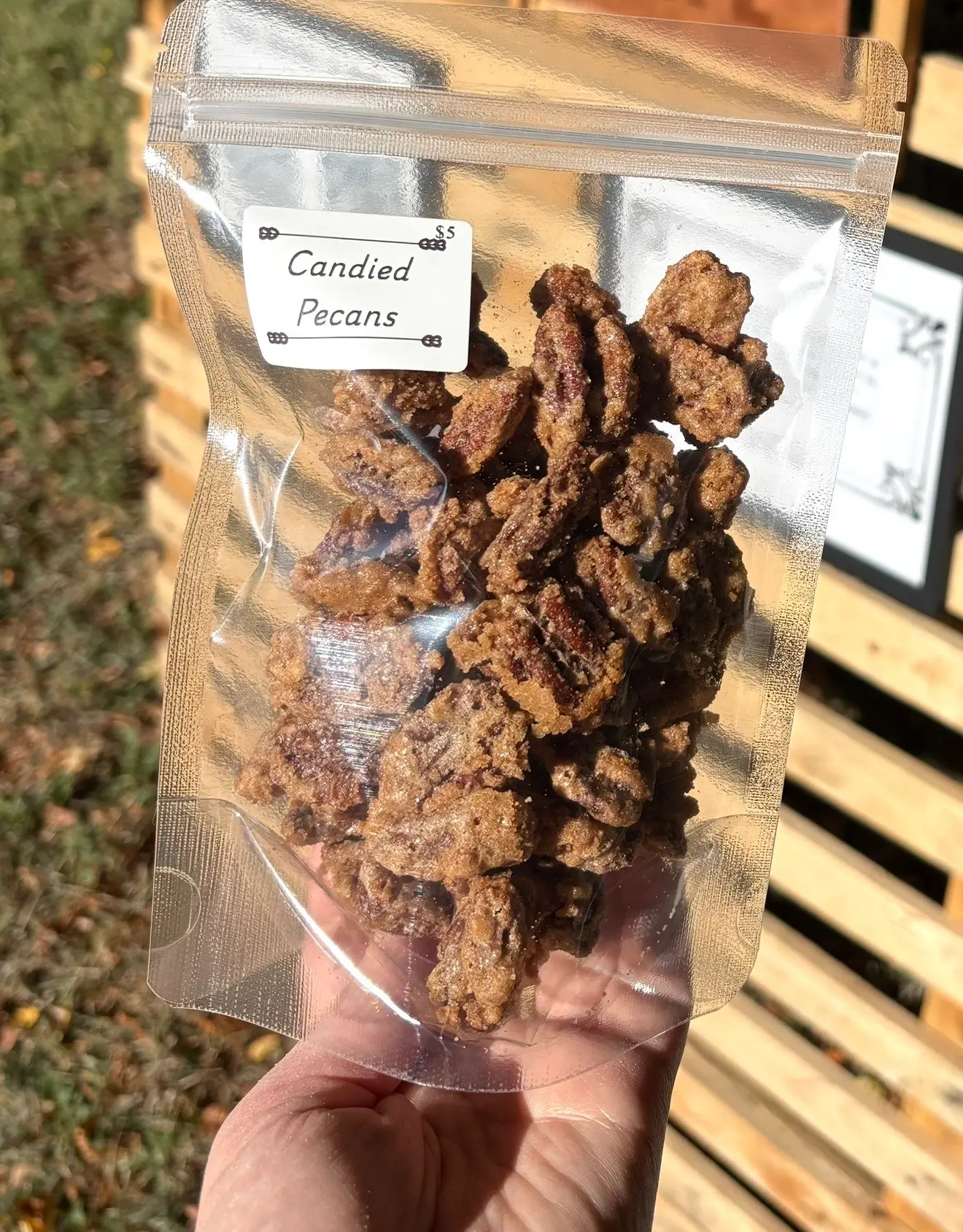 A bag of candied pecans with a Sleepy Apron label reading Candied Pecans, $5