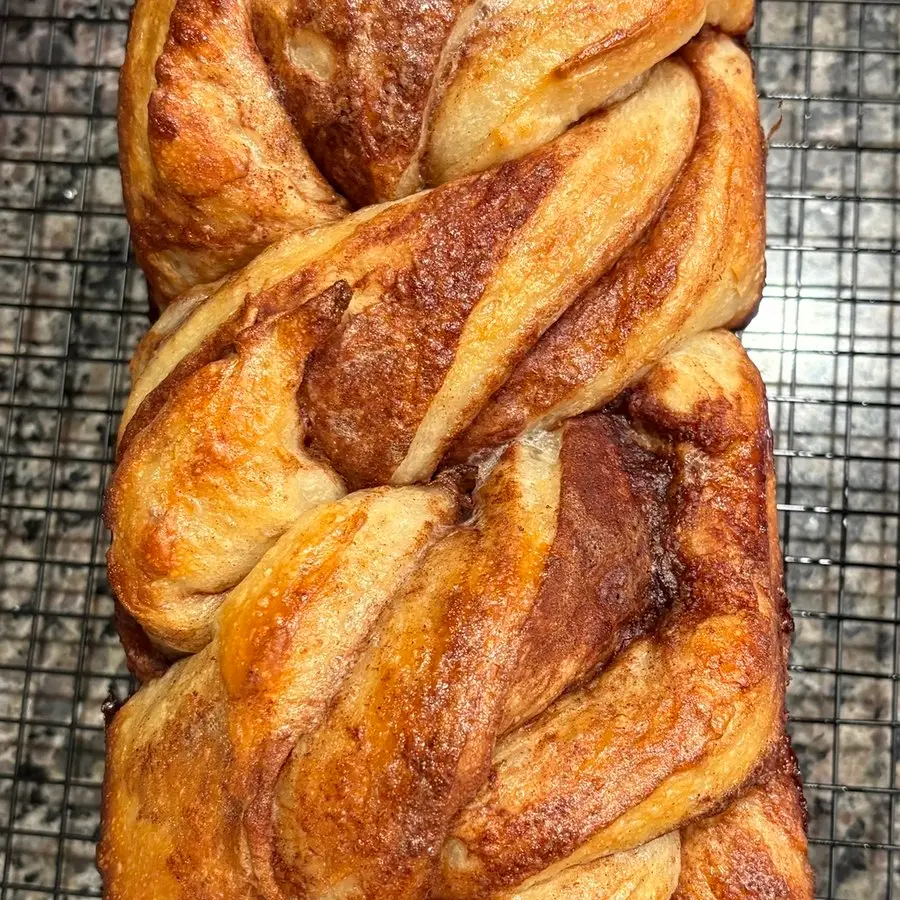 The braided top of a cinnamon swirl sourdough loaf on a cooling rack