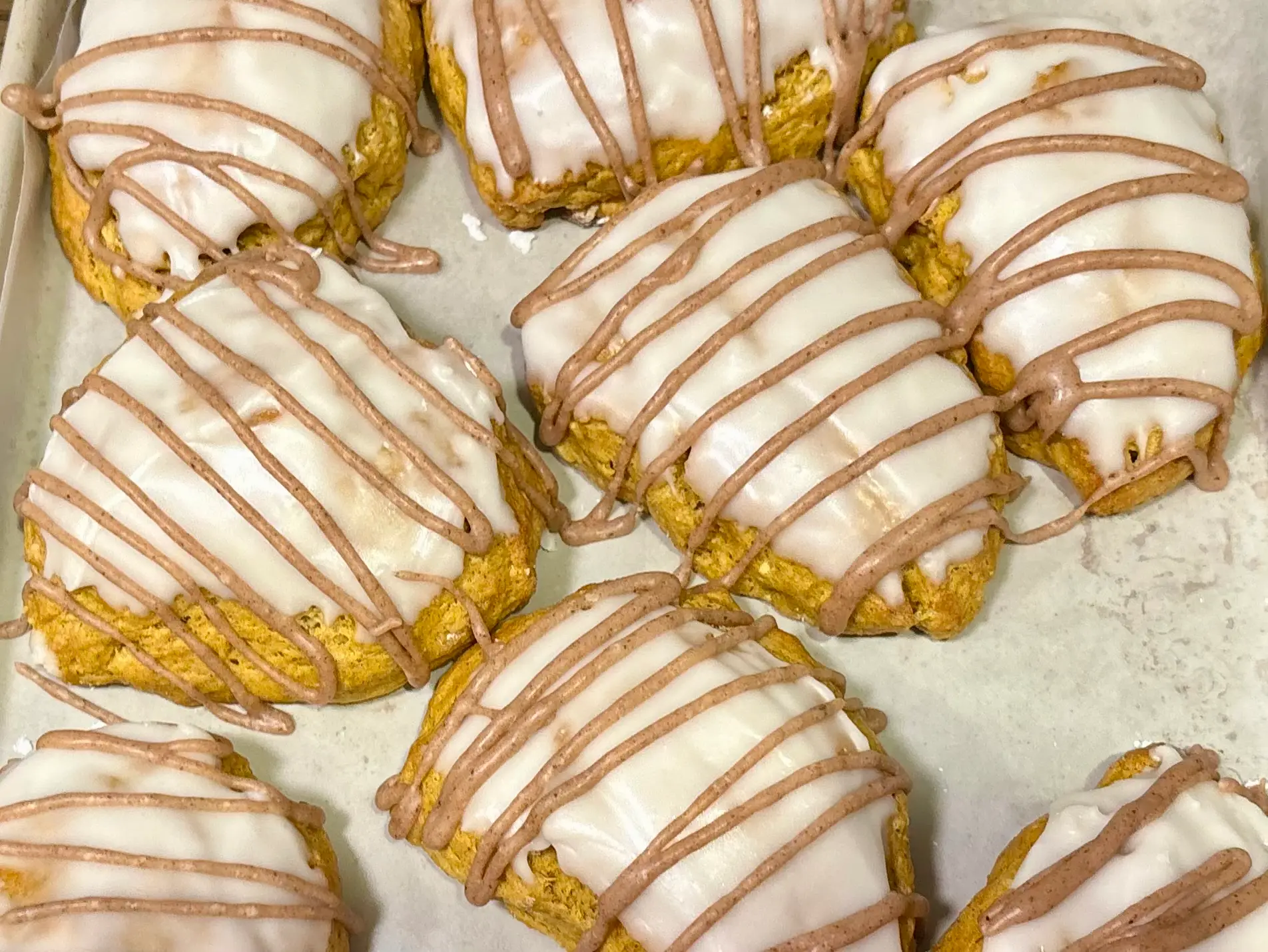 Freshly baked pumpkin scones with white glaze and cinnamon drizzle