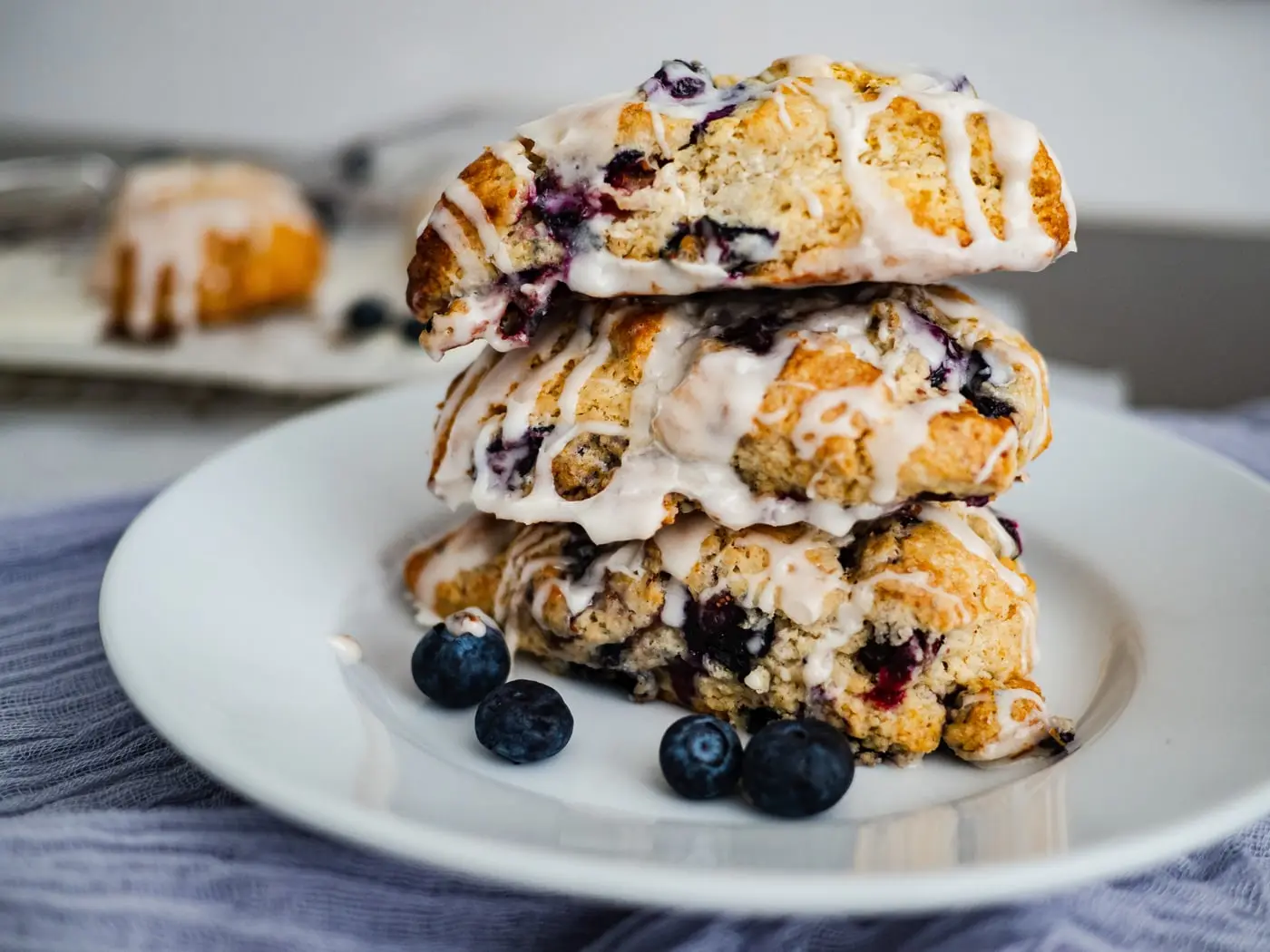 A stack of glazed blueberry scones on a plate