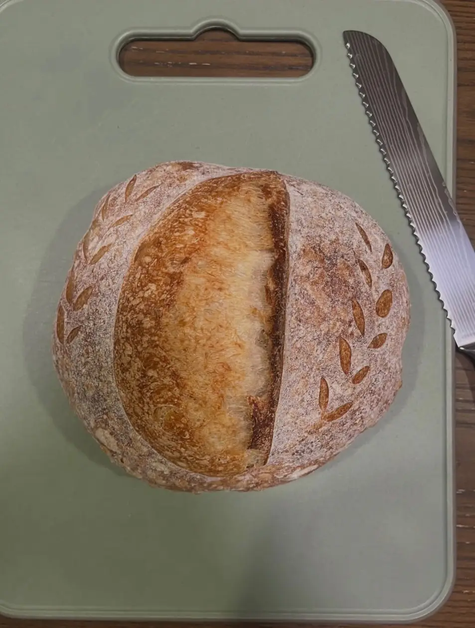 A scored sourdough boule, slashed with a wheat sprig